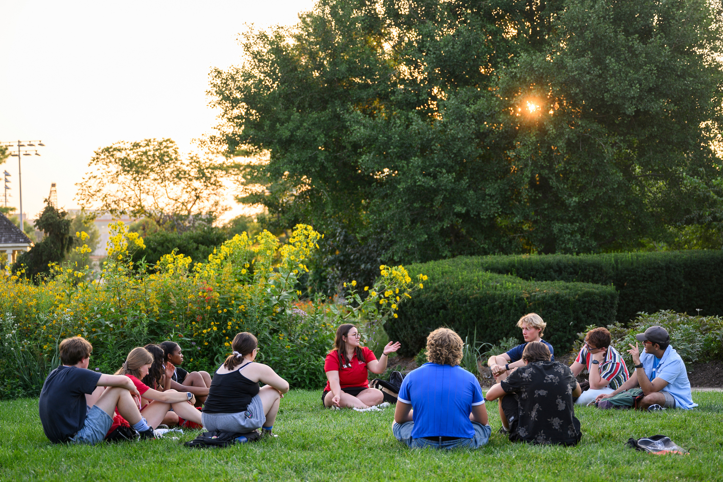 A group of students are sitting in a circle in a garden